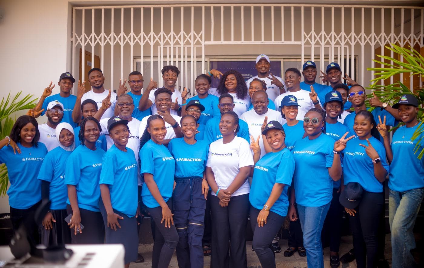The combined FairAction team smiling together at the entrance of the FairAction office in Ibadan