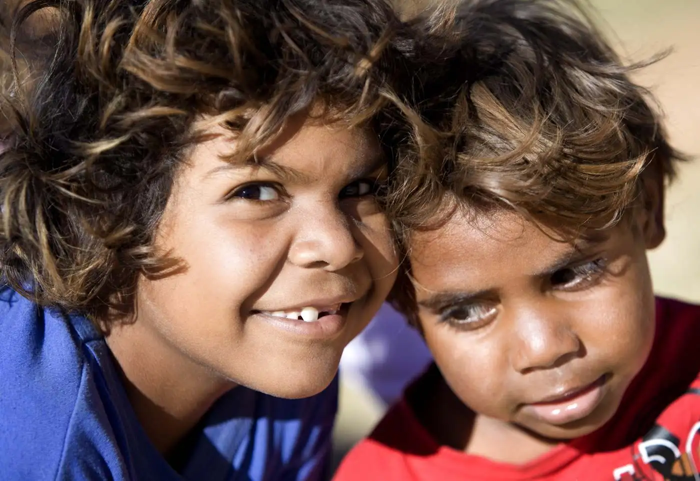 Two Aboriginal children smiling outdoors in remote Australia (stock photograph)