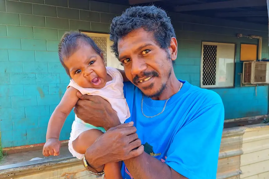 Laramba resident Stanley Fletcher holding his baby outside his home