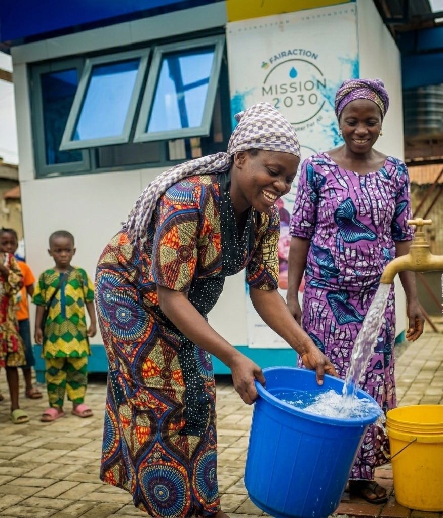 A woman collecting clean water into a bucket at a FairAction Mission 2030 water point